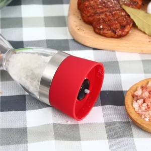 Moulin à sel et poivre manuel en verre double chambre avec poignée en silicone rouge.