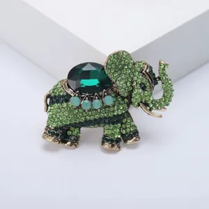 Gros plan d'un détail de broche éléphant en strass vert vintage avec grand cristal.