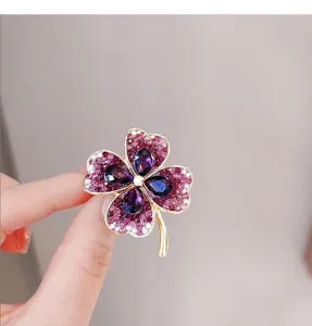 Nahaufnahme des filigranen vierblättrigen Kleeblatt-Broschen-Details mit violetten Kristallen.