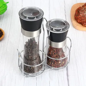Détail de moulin à poivre en verre manuel avec tête en inox et support double bouteille.