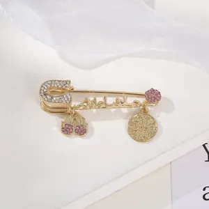 Detailed close-up of a gold-plated safety pin brooch with sparkling rhinestones charms.