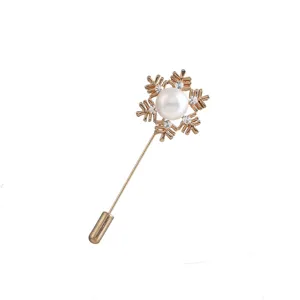 Vintage gold-tone snowflake brooch detail with faux pearl and sparkling crystal accents.