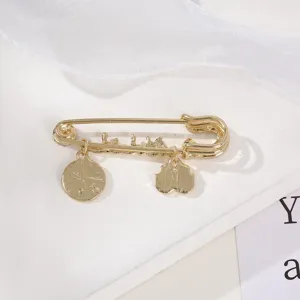 Gold-tone safety pin brooch with cute hanging charms, fashion retro jewelry accessory.