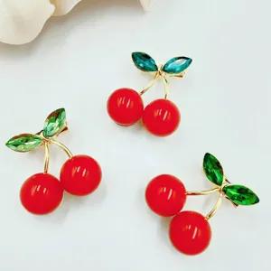 Close-up detail of the cute cherry brooch with sparkling green crystal leaves and bright red pearls.