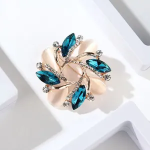 Detailed close-up of exquisite alloy rhinestone brooch with blue crystals and white petals.