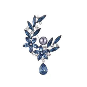 Prachtige blauwe kristallen bloemenbroche met sprankelende strass-steentjes en donkere parel.
