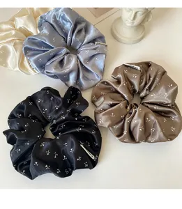 Detailed close-up view of elegant satin floral hair scrunchies set, chic ponytail holders for women.