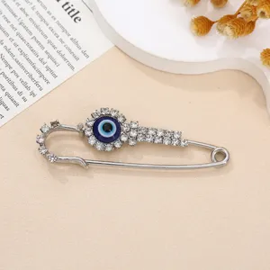Close-up detail van een strass boze oog veiligheidsspeld broche op een beige achtergrond.