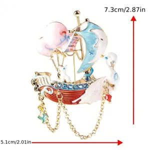 Dettaglio della spilla a barca a vela in smalto con strass, cigno e catenelle pendenti.