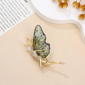 Dettaglio in primo piano dell'elegante spilla fata farfalla con strass e ali verdi.