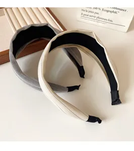 Vue détaillée de serres-tête larges en tissu gris et beige, accessoires minimalistes.