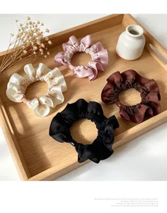 Detailed view of elegant satin ruffle hair scrunchies in four classic colors on wooden tray.