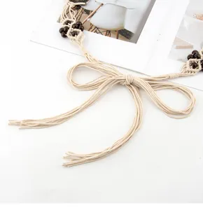 Retro boho μπεζ ζώνη μέσης μακραμέ με ξύλινες χάντρες και φούντες για γυναικεία μόδα.