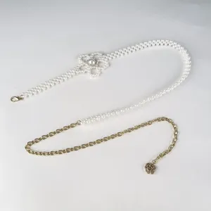 Vue détaillée de l'élégante chaîne de taille en perles avec un joli motif floral.