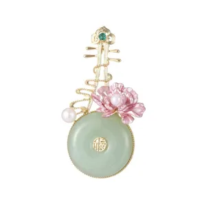 Detailed shot of vintage Chinese style pipa brooch with jade ring and pink enamel flower.