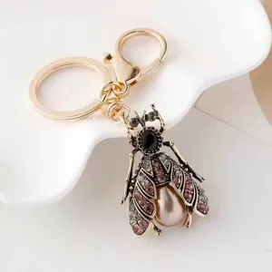 Rhinestone insect keychain with pearl pendant, elegant gold-tone metal bag charm accessory.