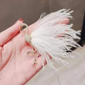 Elegant gold flamingo brooch with soft white feathers, stunning fashion accessory for women.