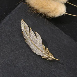 Exquisite goldfarbene Feder-Brosche mit funkelnden Mikropavé-Zirkonia-Details verziert.