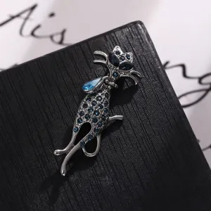 Vue détaillée rapprochée d'une broche chat argentée avec des strass bleu foncé brillants.