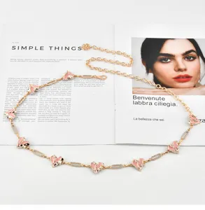 Gold metal chain belt for women with pink enamel heart charms and sparkly rhinestone link details.
