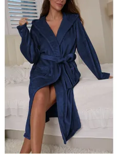Detail view of a cozy dark blue hooded flannel bathrobe worn by a model in bedroom.