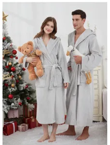 Couple wearing comfortable grey fleece hooded bathrobes in a festive Christmas holiday scene.