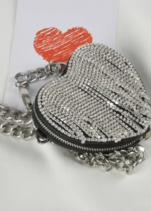 Primer plano detallado del bolso corazón de pedrería brillante con cadena de plata gruesa.