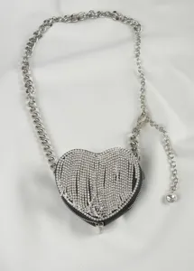Detalle de bolso de corazón con pedrería, mini bolso brillante con correa de cadena metálica plateada.