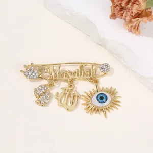 Goldfarbene Legierung böser Blick Brosche mit glitzernden Strasssteinen und feinen Anhängern.
