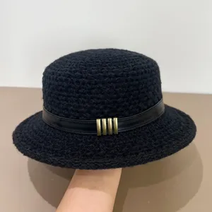 Detailed view of the black knitted bucket hat showing the leather strap and metal buckle accent.