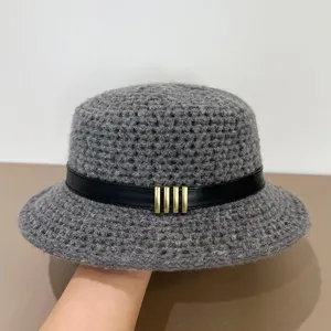 Close-up detail of grey crochet bucket hat featuring black leather belt and metal bars.