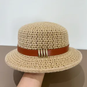Detailed view of a woven flat-top bucket hat with brown leather belt and gold metal buckles.