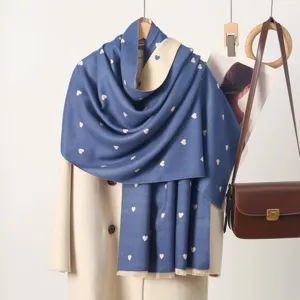 Detail shot of blue cashmere feel scarf featuring cute white heart patterns for cold winter days.