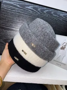 Detailed shot of winter knitted wool hats in three colors grey white and black with chic metal decor.