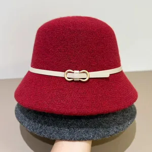 Detail shot of a stylish red wool bucket hat with chic beige belt buckle and dark grey layer.