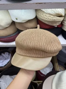 Khaki knitted newsboy hat detail showing textured woolen fabric and smooth leather-like brim.