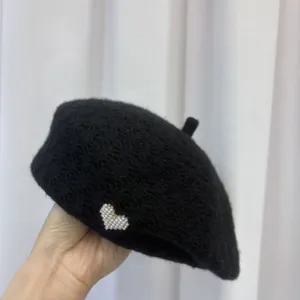 Black wool blend beret hat featuring an elegant pearl heart detail, closeup product view.