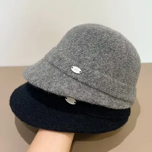 Chic winter wool blend bucket hat featuring a wide brim and a nice metal badge detail now.