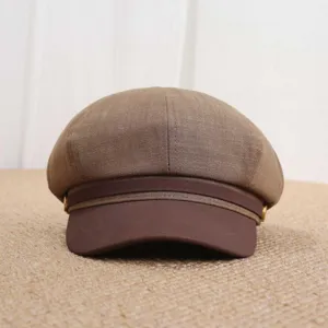 Gros plan sur la casquette de gavroche marron, design octogonal classique avec boutons métalliques.