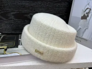 Close-up detail of winter warm knitted bucket hat in cream white with crystal letter decor.
