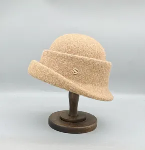 Détail rapproché d'un élégant chapeau cloche en laine à bord roulé avec accent métallique.