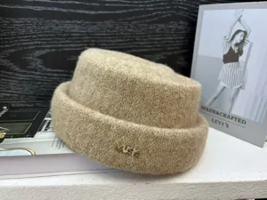 Winter knitted bucket hat with chic metal letter embellishment, warm and stylish detail view.