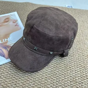 Braune Wildleder Flachkopf Mütze Detail zeigt Nieten und strukturierte Stoffgestaltung.
