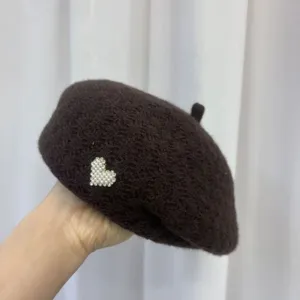Detail view of dark brown wool beret with pearl heart charm, a stylish winter hat