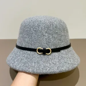 Closeup of gray knitted bucket hat featuring a chic black thin belt with gold double buckle.