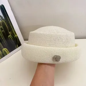 Vista di dettaglio dell'elegante cappello in maglia con una brillante spilla floreale in strass.