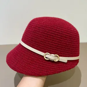 Detailed shot of a red knitted cloche hat with a white belt and metal ring buckle.