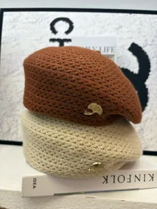 Detailansicht der Strickbarette in Braun und Beige mit schickem Metall-Blatt-Abzeichen.