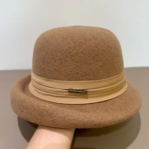 Close-up detail of a brown wool felt bowler hat featuring a ribbon and rhinestone metal badge.