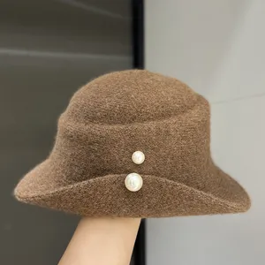Close-up of a brown woolen bucket hat featuring elegant double pearl decoration.